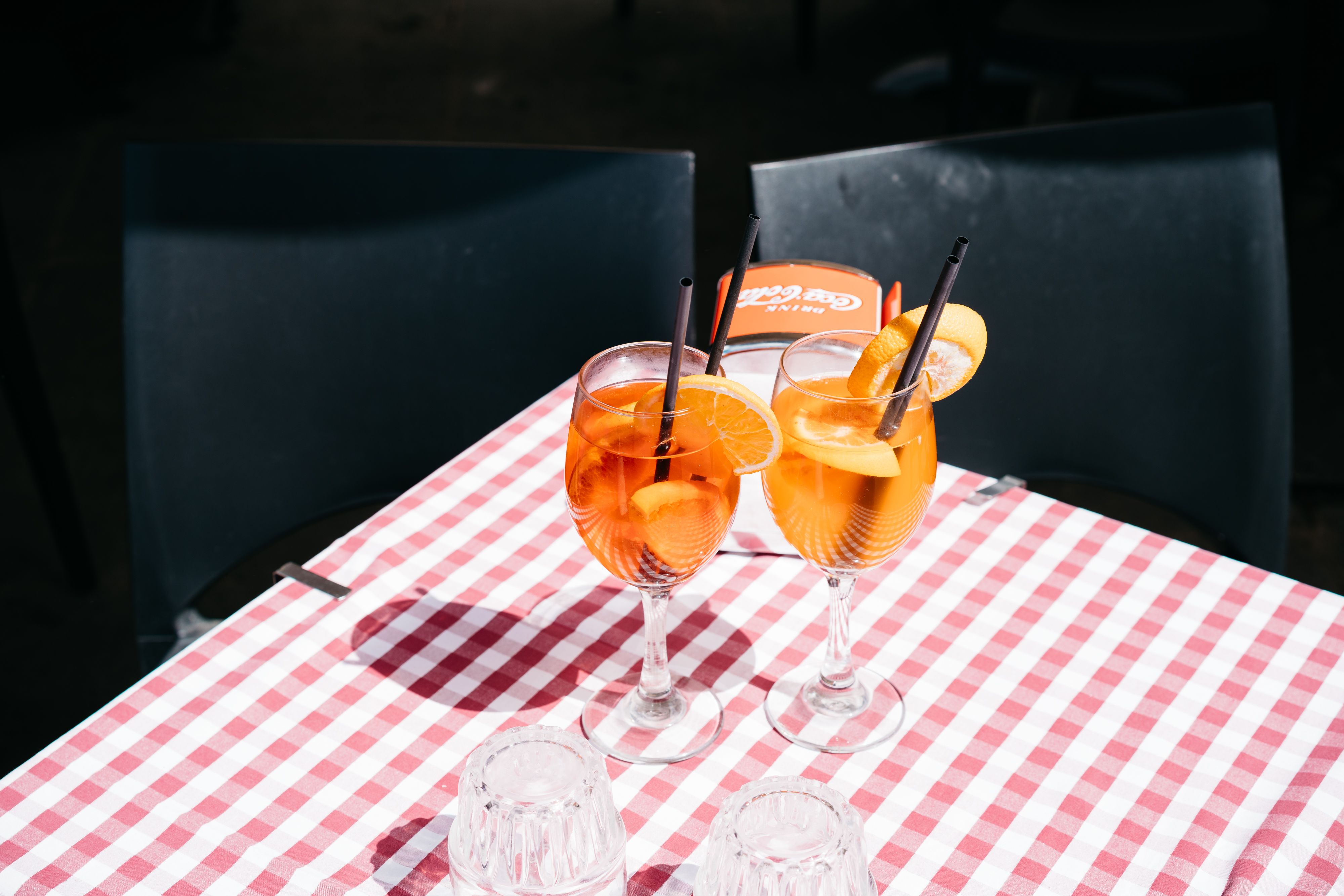 Two Italian aperitivo spritz cocktails on a checkered tablecloth